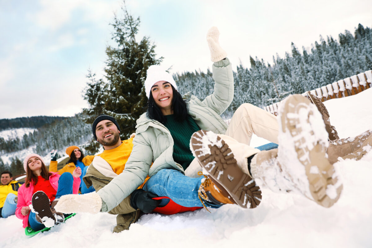 Group of friends having fun and sledding on snowy day. Winter vacation @ Deposit Photos